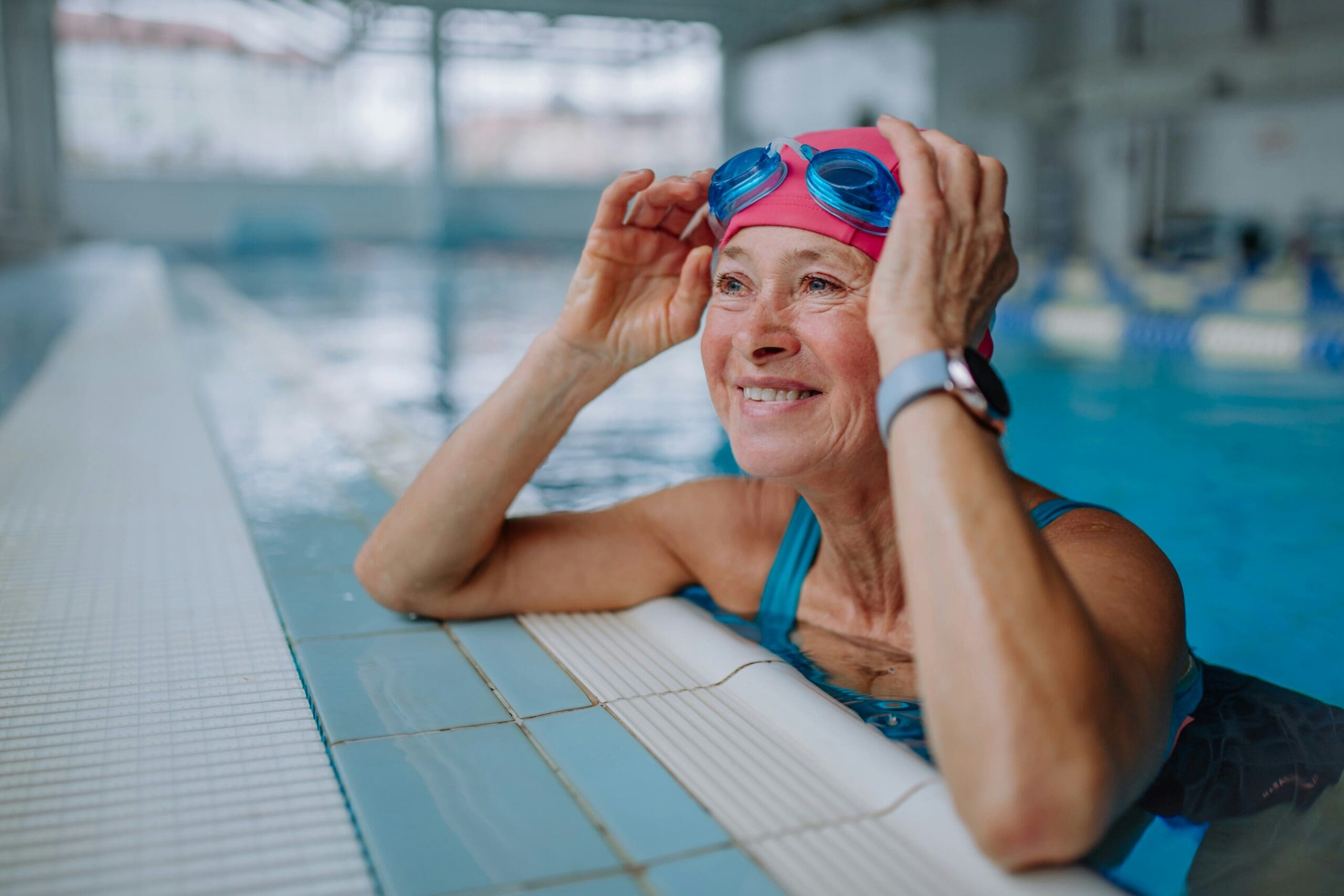 Femme ainée qui fait un cour de natation dans une piscine intérieure
