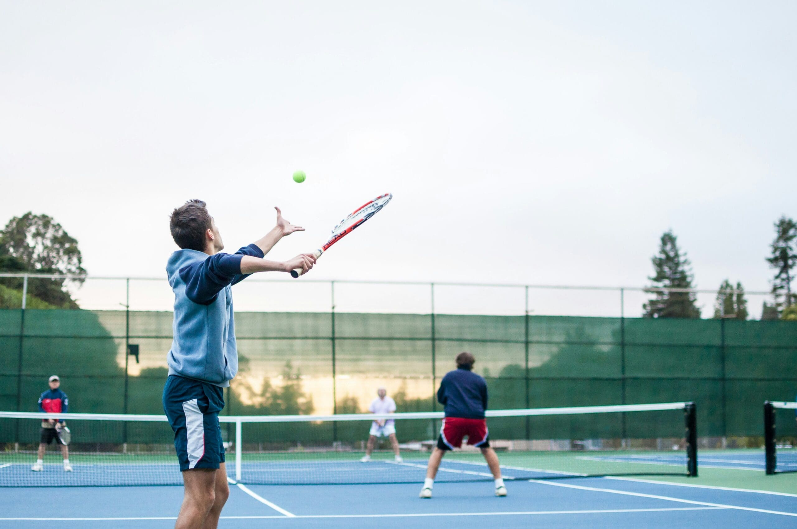 Groupe de personne qui joue au tennis sur un terrain extérieur