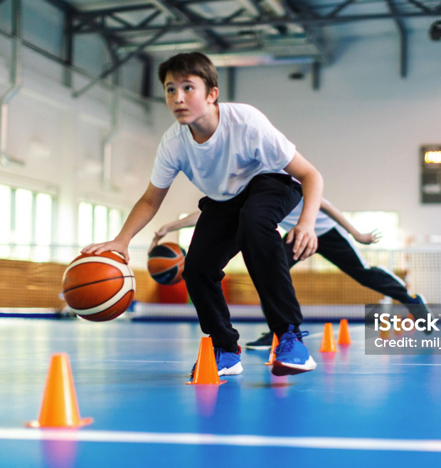 Un élève dans un gymnase d'école qui joue au basketball avec un ballon