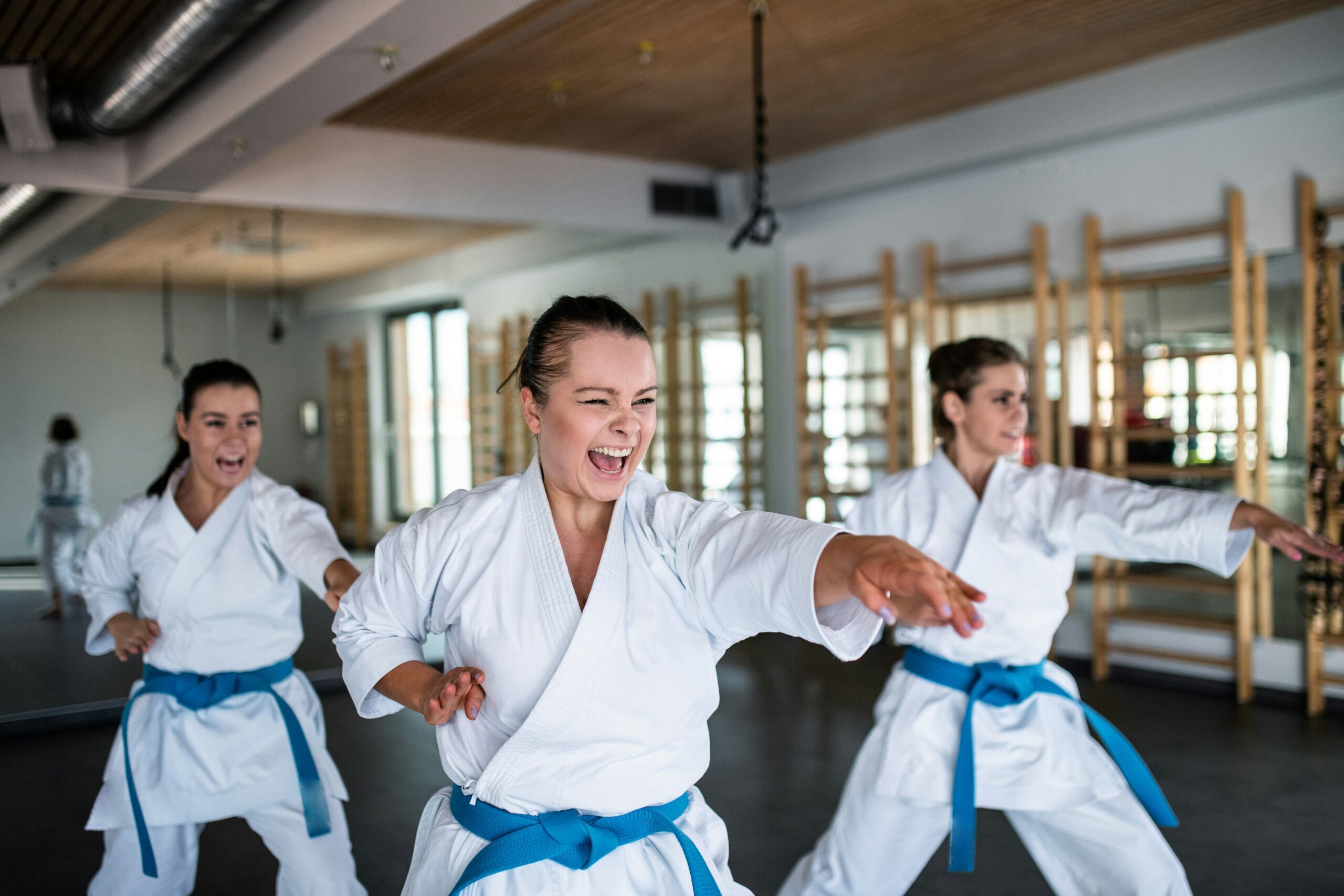 Trois adolescentes suivent un cours de karaté dans un gymnase ou dans un dojo