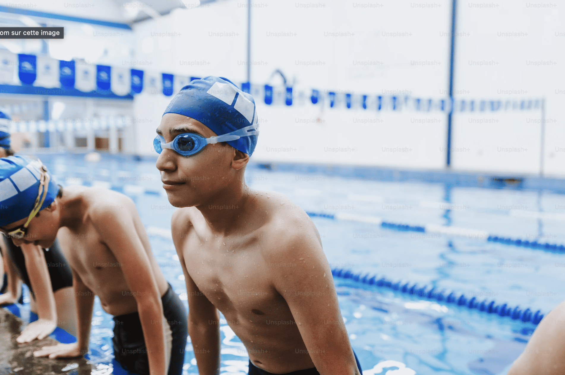 Un groupe de jeune garçcon qui suivent un cours de natation dans une piscine