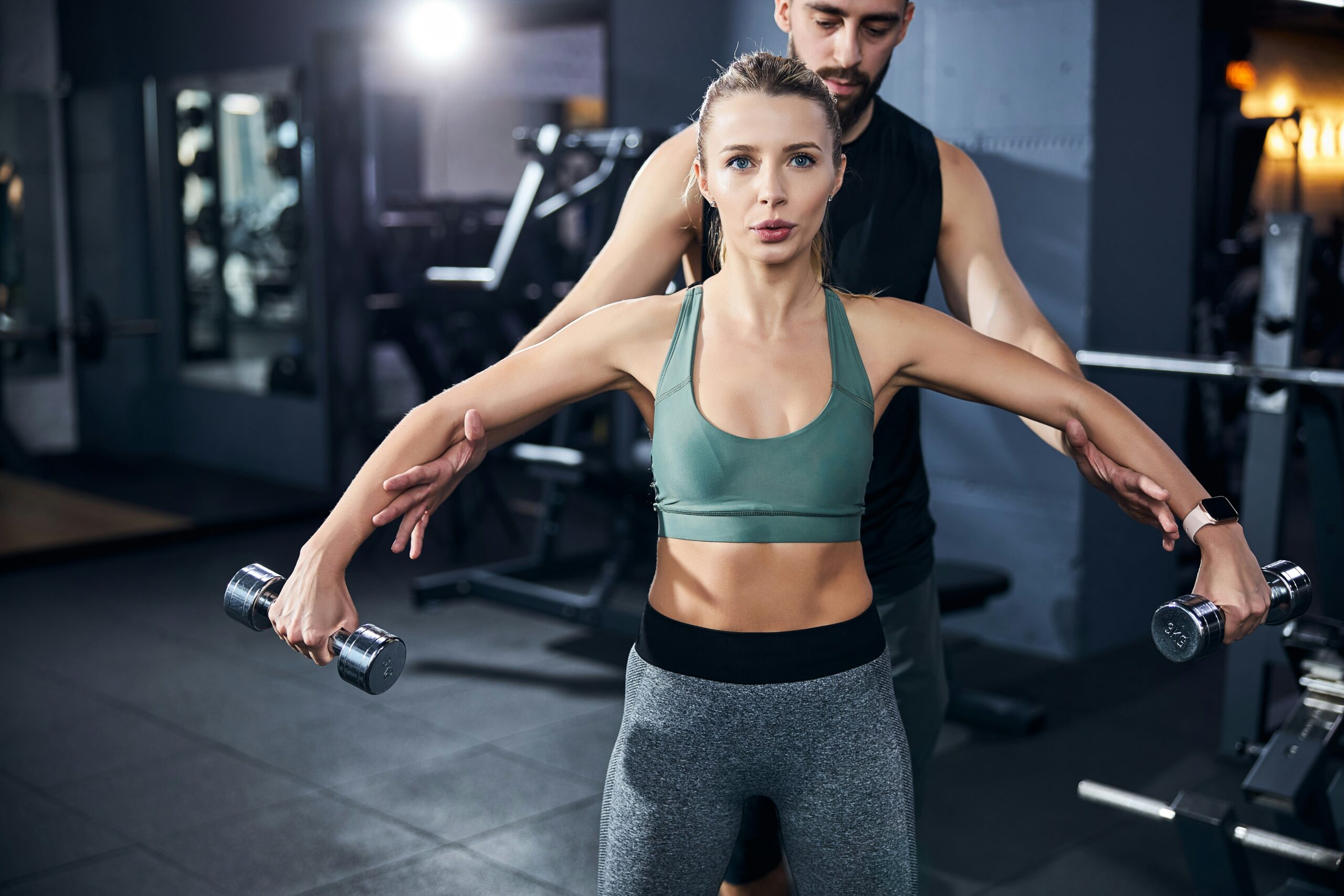 Femme qui s'entraine dans un gym / centre d'entrainement avec un entraineur