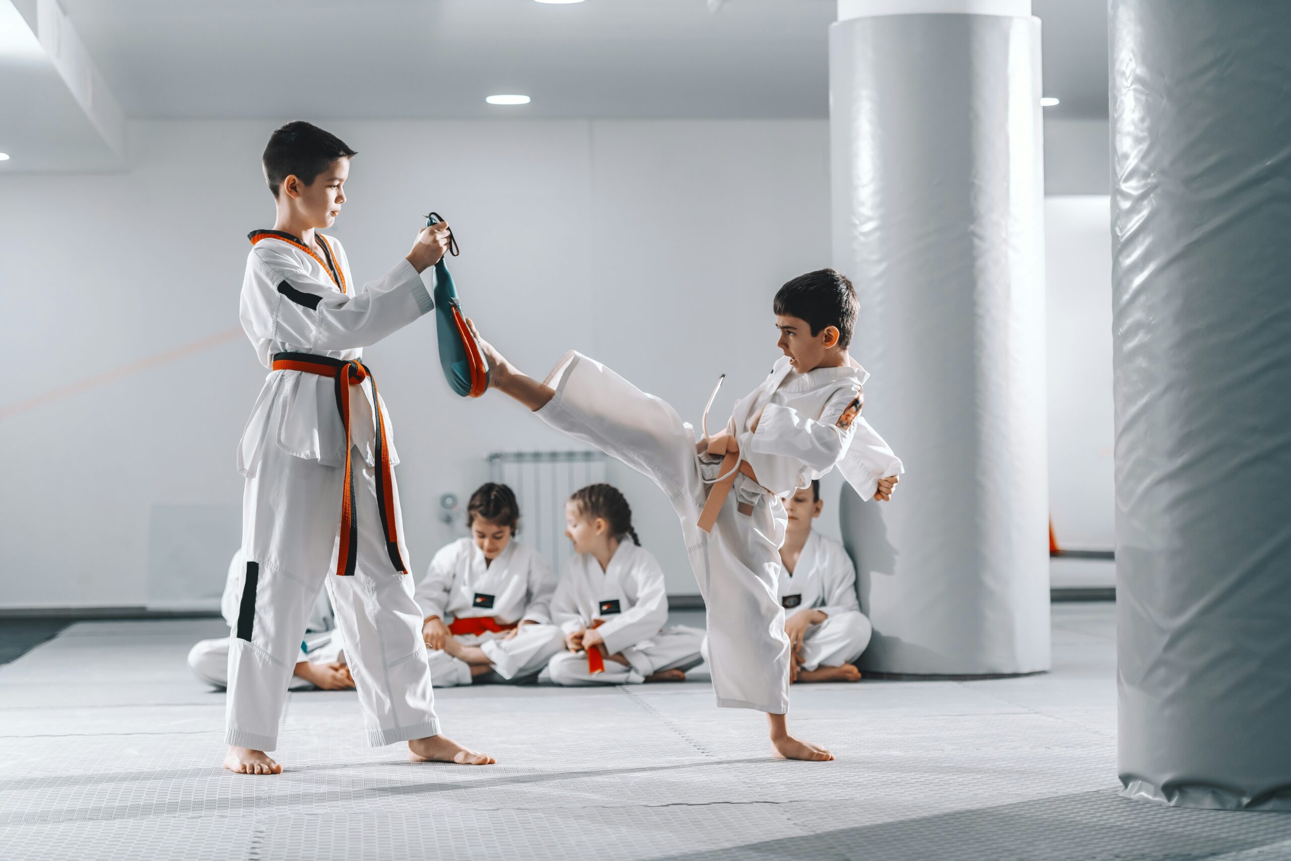 Des élèves qui suivent un cours de karaté et de taekwondo dans une classe